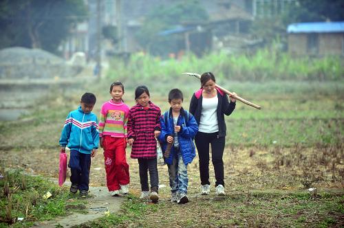 這是2月25日,梁麗娜與路上碰到的小學(xué)生一起回村。新華社記者 黃孝邦 攝