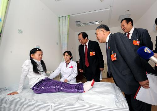 3月9日,全國(guó)人大代表張伯禮(前)、趙步長(zhǎng)(后右一)和全國(guó)政協(xié)委員王承德(后右二)在調(diào)研中看望接受治療的小女孩。新華社記者 何俊昌 攝