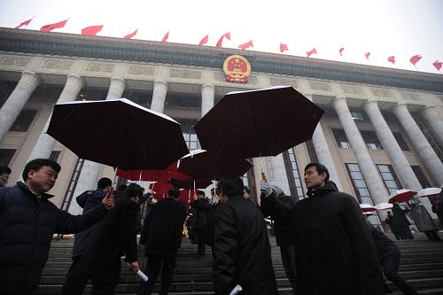 3月14日,第十一屆全國人民代表大會第三次會議將在北京人民大會堂舉行閉幕會。北京下起了雨夾雪,工作人員打著傘迎接代表。新華社記者 金良快 攝