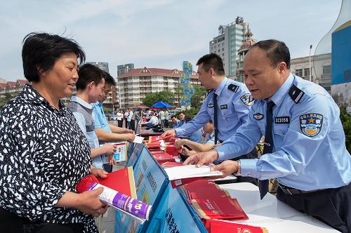 5月15日,天津公安局塘沽分局民警在塘沽外灘公園向人們發(fā)放宣傳資料,現(xiàn)場講解假幣的危害和識別技巧。新華社發(fā)(趙永明 攝)