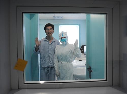 5月20日,被隔離者小秦和照顧他的護(hù)士向記者鏡頭招手。新華社記者 李文 攝