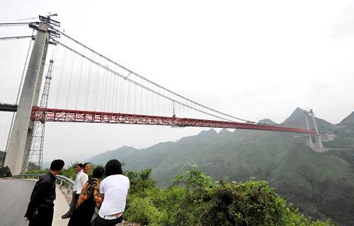 6月21日,幾位行人在觀看壩陵河特大橋。壩陵河大橋是滬瑞國(guó)道主干線(上海至云南瑞麗)貴州境內(nèi)鎮(zhèn)寧到勝境關(guān)高速公路上的一座特大型橋梁,大橋主跨1088米,橋面距峽谷谷底約370米。目前,壩陵河特大橋正在進(jìn)行橋面施工,預(yù)計(jì)今年年底建成。壩陵河特大橋建成后,將使從黃果樹風(fēng)景區(qū)到關(guān)嶺縣城的里程縮短20公里,車程從半小時(shí)縮短到5分鐘。 新華社記者 楊楹 攝