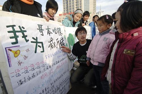 12月5日,一名大學(xué)生在向幾位小朋友講解節(jié)能減排常識(shí)。 新華社記者 李健 攝