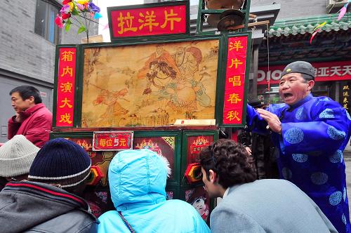 2月5日,中外游客在大柵欄商業(yè)文化廟會上觀看老北京拉洋片。當(dāng)日,作為“宣武請您來過年”先期啟動的項目,北京第二屆大柵欄商業(yè)文化廟會開幕。拉洋片、沿街叫賣、老字號小吃售賣、老字號商鋪促銷活動等讓中外游客體驗透出濃濃年味的民俗風(fēng)情。新華社發(fā)(鄭永 攝)