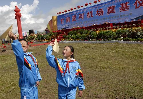 9月7日,在甘肅甘南州夏河機(jī)場(chǎng)奠基儀式現(xiàn)場(chǎng),夏河縣阿木去乎中心小學(xué)學(xué)生尕藏道吉(左)和同學(xué)拉毛卓瑪一起玩紙飛機(jī)。 新華社發(fā)(后俊 攝)