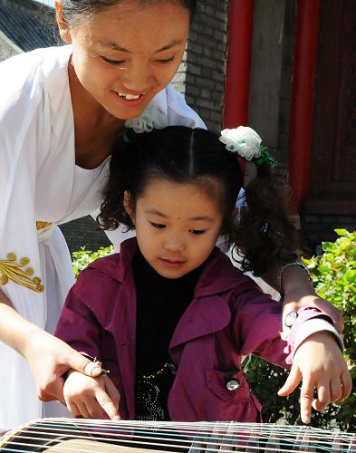 9月22日,文廟國樂團的樂手在教授小朋友彈奏古箏。 當(dāng)日,吉林省長春市文廟免費開放,并向廣大市民免費發(fā)放“福餅”,教市民免費學(xué)古箏,讓人們度過一個傳統(tǒng)味兒十足的中秋假期。 新華社記者 常亦殊 攝