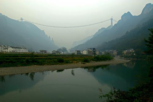 圖為橫跨德夯大峽谷的大橋全景(10月20日攝)。10月20日,建設中的矮寨特大懸索橋的主纜完成了最后一根索股的架設,標志著大橋的索塔、主纜、鋼桁梁三大主體工程完成了兩項。矮寨特大懸索橋是國家高速公路重點規(guī)劃的8條西部通道之一的長沙至重慶通道,湖南段的吉(首)茶(峒)高速公路中的重點工程,在吉首市矮寨鎮(zhèn)上空330米處橫跨德夯大峽谷。橋身全長約1073.65米,其中懸索橋的主跨1176米。工程概算9.2億元,預計2011年年底建成通車。 新華社記者 范軍威 攝