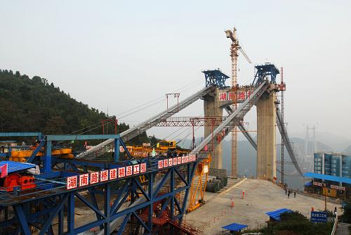 圖為建設中的矮寨特大懸索橋(10月20日攝)。 10月20日,建設中的矮寨特大懸索橋的主纜完成了最后一根索股的架設,標志著大橋的索塔、主纜、鋼桁梁三大主體工程完成了兩項。 矮寨特大懸索橋是國家高速公路重點規(guī)劃的8條西部通道之一的長沙至重慶通道,湖南段的吉(首)茶(峒)高速公路中的重點工程,在吉首市矮寨鎮(zhèn)上空330米處橫跨德夯大峽谷。橋身全長約1073.65米,其中懸索橋的主跨1176米。工程概算9.2億元,預計2011年年底建成通車。 新華社記者范軍威攝
