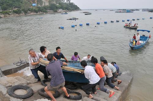 10月21日,在廣東深圳市南澳漁港,人們將船只搬運(yùn)上岸,防御臺(tái)風(fēng)“鲇魚”。 新華社發(fā)(李堅(jiān)強(qiáng) 攝)