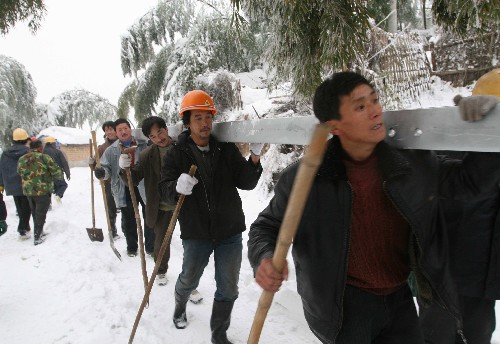 1月22日,安徽電力施工人員和當?shù)厝罕娺\送搶修受損輸電線路的物資。