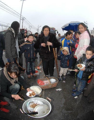 京珠高速公路湖南湘潭馬家河收費(fèi)站滯留的旅客就地購(gòu)買商販的食物(1月27日攝)。