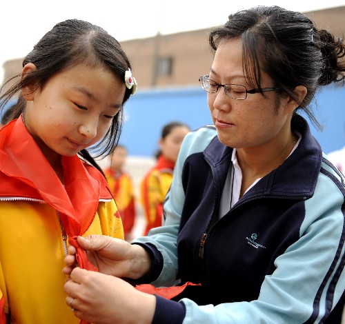 5月27日,太原市迎澤區(qū)第一實(shí)驗(yàn)小學(xué)的常耀梅老師(右)在入學(xué)儀式上為來(lái)自四川綿竹的六年級(jí)學(xué)生劉媛媛系上紅領(lǐng)巾。 當(dāng)日,太原市迎澤區(qū)第一實(shí)驗(yàn)小學(xué)迎來(lái)了首批四川地震災(zāi)區(qū)的6位入學(xué)兒童。學(xué)校為這6位孩子免去所有費(fèi)用,并為他們安排宿舍和提供生活用品,還在校食堂內(nèi)專設(shè)了川菜窗口。
