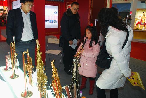 11月29日,一名小女孩在北京文博會(huì)上試吹薩克斯管。新華社發(fā)(韓路 攝)