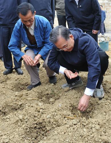4月4日,在安龍縣納賴村,溫家寶走到地里與村民們一道施肥、澆水,種下小青瓜。新華社記者 李學(xué)仁 攝