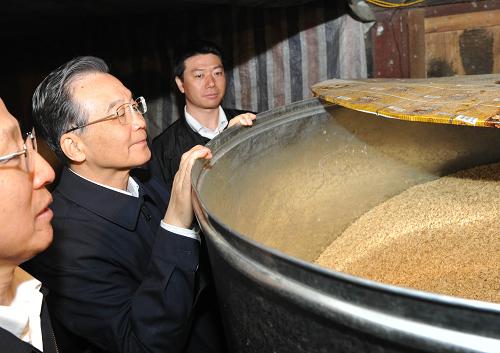4月4日,在安龍縣納賴村村民楊文明家,溫家寶察看他家的糧倉里還有多少稻米。新華社記者 李學(xué)仁 攝