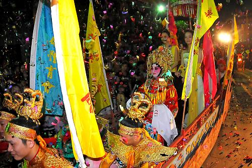 6月18日深夜,在梧州龍母廟,由演員扮演的“龍母”坐在“龍船”中向游客“賜福”。 新華社發(fā)(何鎏 攝)