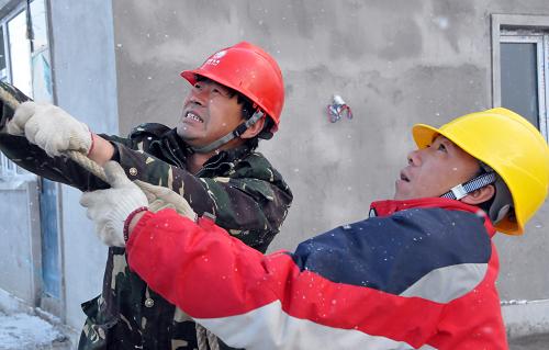 10月25日,吉林省水利水電有限公司安圖分公司的工作人員在為受災(zāi)群眾住宅新區(qū)安裝電力線路。新華社記者 齊海山 攝