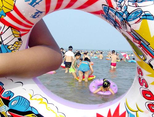 2004年8月5日,在山東日照國家森林公園海濱風(fēng)景區(qū),游人盡情享受藍(lán)天、碧海、沙灘帶來的樂趣。新華社發(fā)