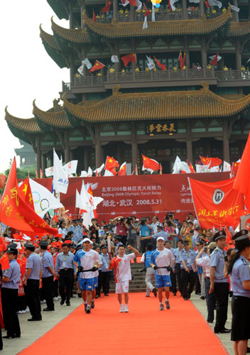 5月31日,第一棒火炬手楊威(中)在火炬?zhèn)鬟f中。當(dāng)日,北京奧運(yùn)圣火在湖北武漢傳遞。 新華社記者安治平攝