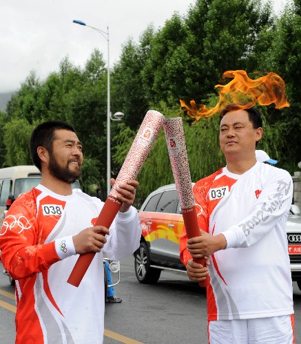 6月21日,火炬手張云寶(右)與下一棒火炬手才讓扎西交接。當(dāng)日,北京奧運會圣火傳遞活動在西藏拉薩舉行。 新華社記者覺果攝