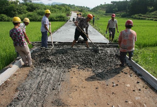 7月23日,筑路工人在緊張澆注通往休寧縣萬(wàn)安鎮(zhèn)福寺村的水泥路。這是該縣最后幾條正在建設(shè)中的通村公路之一。地處皖南山區(qū)的安徽休寧縣2006年啟動(dòng)“村村通公路”工程,新建通村公路110多條,里程達(dá)347公里。到目前為止,全縣90%的村已經(jīng)通公路。 新華社發(fā)(倪受兵 攝)