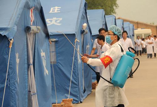 6月16日,在河北省井陘縣的實戰(zhàn)演練中,防疫人員對“安置點”進行消毒。 當日,河北省舉行了自然災害救助應急預案演練,以提高各級政府應對突發(fā)重大自然災害緊急救援的組織協(xié)調(diào)能力,增強群眾防災減災意識。演練以1996年8月上旬發(fā)生在石家莊西部山區(qū)特大洪澇災害為背景,在石家莊市、井陘縣、贊皇縣、元氏縣、鹿泉市同時展開。演練包括應急響應、轉移安置、災后救助等內(nèi)容,共轉移安置“受災群眾”近10萬人,動用車輛近300輛。 新華社記者 鞏志宏 攝