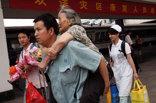 6月17日,工作人員將一名病愈出院的老人背上火車(chē)。新華社發(fā)(鄭鵬 攝)