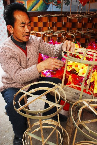 11月23日,一名村民在淄博市北郊鎮(zhèn)豐樂村一家庭手工作坊內(nèi)制作花籃。新華社發(fā)(董乃德 攝)