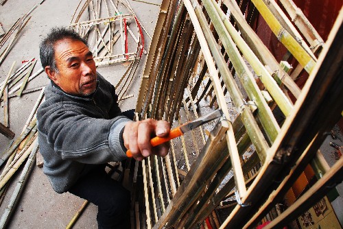 11月23日,一名村民在淄博市北郊鎮(zhèn)豐樂村一家庭手工作坊內(nèi)制作旱船船面。新華社發(fā)(董乃德 攝)
