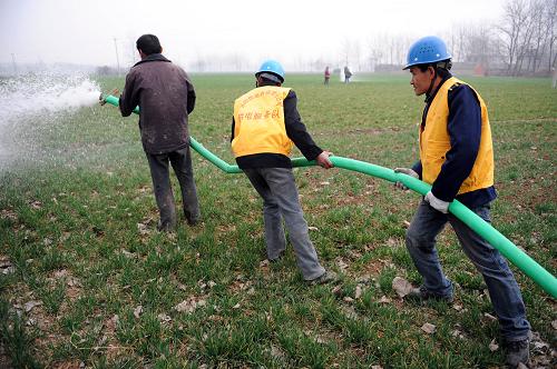 2月15日,在安徽省渦陽(yáng)縣西陽(yáng)鎮(zhèn)郭寨村,供電服務(wù)隊(duì)員幫村民引水澆苗。新華社發(fā)(張延林 攝)