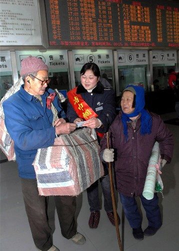 1月24日,周山濱汽車客運(yùn)站服務(wù)員金嵐(中)協(xié)助兩位老人購票并送他們上車。新華社記者 何俊昌 攝