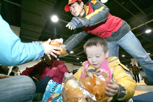 1月30日,杭州市下城區(qū)的志愿者將募集到的食品免費(fèi)發(fā)放給和平會(huì)展中心臨時(shí)駐留點(diǎn)里的滯留旅客。 針對(duì)大批返鄉(xiāng)旅客滯留杭州火車站、杭州火車東站和各大長(zhǎng)途汽車站的情況,杭州市從1月27日起開辟劇院、會(huì)展中心、體育館等公共場(chǎng)所并搭建臨時(shí)帳篷,作為滯留旅客的臨時(shí)駐留點(diǎn)。至1月30日下午,這些駐留點(diǎn)已先后接待約10萬人次的滯留旅客。 新華社發(fā)(李忠 攝)