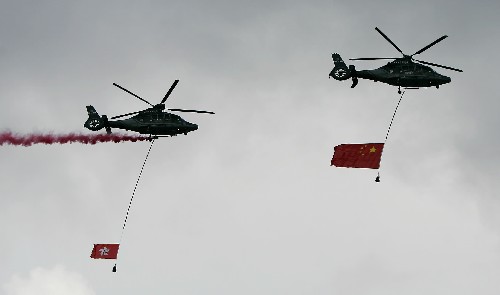 7月1日,2架分別懸掛著國旗和香港特區(qū)區(qū)旗的直升機(jī)在升旗儀式結(jié)束后從空中飛過。新華社記者 周磊 攝