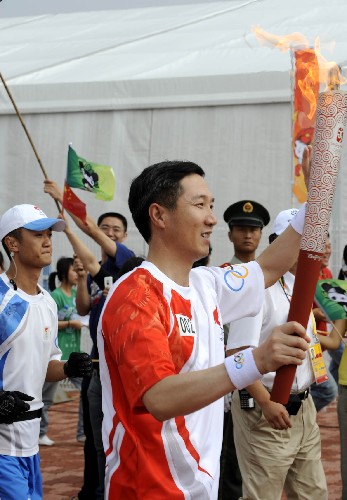 7月21日,火炬手陳愛(ài)新手持火炬進(jìn)行傳遞。當(dāng)日,北京奧運(yùn)圣火在山東省青島市傳遞。 新華社記者李紫恒攝
