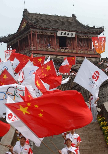 7月30日,人們?cè)诨鹁鎮(zhèn)鬟f起點(diǎn)老龍頭澄海樓前揮舞旗幟迎接圣火。當(dāng)日,北京奧運(yùn)圣火在河北省秦皇島市傳遞。 新華社記者鞏志宏攝