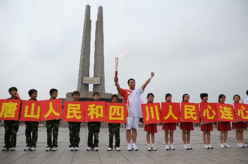 7月31日,火炬手宋志永在唐山抗震紀(jì)念碑前展示火炬。他和他的12名農(nóng)民兄弟因自費(fèi)去災(zāi)區(qū)抗災(zāi)被稱為“唐山十三義士”。當(dāng)日,北京奧運(yùn)圣火在河北省唐山市傳遞。 新華社記者鞏志宏攝