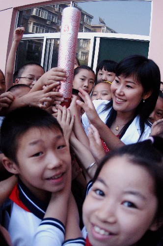9月1日,在濟南市經(jīng)十一路小學(xué)舉行的主題為“享受奧運精彩,開創(chuàng)美好未來”的開學(xué)典禮上,同學(xué)們與奧運火炬手一起觸摸火炬。 新華社發(fā)(趙曉明 攝)