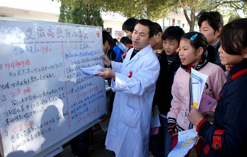 11月29日,在江西樂平市后港鎮(zhèn)新樂中學(xué)校園,來自樂平市紅十字會醫(yī)院的醫(yī)務(wù)人員向留守學(xué)生講解艾滋病預(yù)防知識。連日來,樂平市紅十字會醫(yī)院抽調(diào)業(yè)務(wù)骨干人員,組成多個“防艾”宣傳小分隊深入到農(nóng)村各中小學(xué)內(nèi),對留守學(xué)生進(jìn)行艾滋病相關(guān)知識的教育,免費發(fā)放有關(guān)預(yù)防艾滋病的圖書、手冊等宣傳資料,以提高學(xué)生們對艾滋病的科學(xué)認(rèn)識。新華社發(fā)(朱定文 攝)
