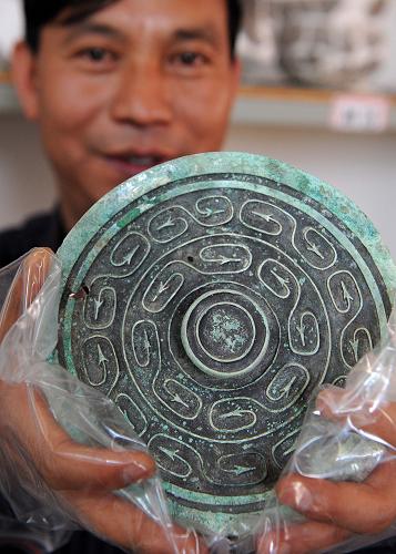 3月12日,一名工作人員在展示金蓮山古墓葬群中出土的青銅扣飾。新華社記者 藺以光 攝