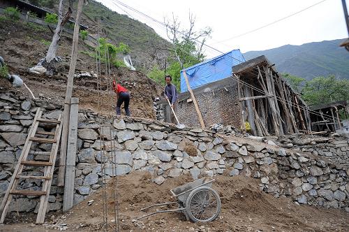 4月23日,梁家山社村民李占林(右)在建新房。