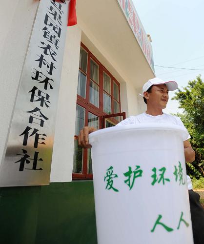6月5日,長(zhǎng)沙縣果園鎮(zhèn)農(nóng)村環(huán)保合作社保潔員陳又專(zhuān)拿起保潔桶準(zhǔn)備開(kāi)始一天的工作。6月3日,一個(gè)市場(chǎng)化運(yùn)營(yíng)、致力于農(nóng)村生活垃圾分類(lèi)處理機(jī)制建設(shè)的農(nóng)村環(huán)保合作社在湖南省長(zhǎng)沙縣果園鎮(zhèn)成立。果園鎮(zhèn)農(nóng)村環(huán)保合作社按照“分戶(hù)收集、分類(lèi)減量、村民自治、政府補(bǔ)貼、合作社運(yùn)作”的機(jī)制,在全鎮(zhèn)每戶(hù)建立小型垃圾池,并在每個(gè)村招募保潔員上門(mén)收購(gòu)垃圾,農(nóng)戶(hù)只需每月交納5元保潔費(fèi)便可享受到上門(mén)分類(lèi)回收垃圾的“環(huán)保服務(wù)”。保潔員通過(guò)分類(lèi)收集處理,將可降解垃圾在垃圾堆漚池填埋處理,將不可降解的可利用垃圾送至廢品公司,不可降解有害垃圾集中送至鎮(zhèn)壓縮中轉(zhuǎn)站,然后統(tǒng)一運(yùn)送到固體廢棄物填埋場(chǎng)集中填埋。通過(guò)這種方法,在農(nóng)村生活垃圾中只剩下10%左右的不可利用垃圾被送到縣里的垃圾場(chǎng)進(jìn)行填埋,極大地節(jié)約了土地資源和垃圾處理成本,同時(shí)為農(nóng)戶(hù)們帶來(lái)了一個(gè)更加清潔健康的生產(chǎn)生活環(huán)境。 新華社記者 李尕 攝