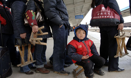 2月18日,在安徽安慶西站,一位小朋友坐著自帶的馬扎與父母一起等車。
