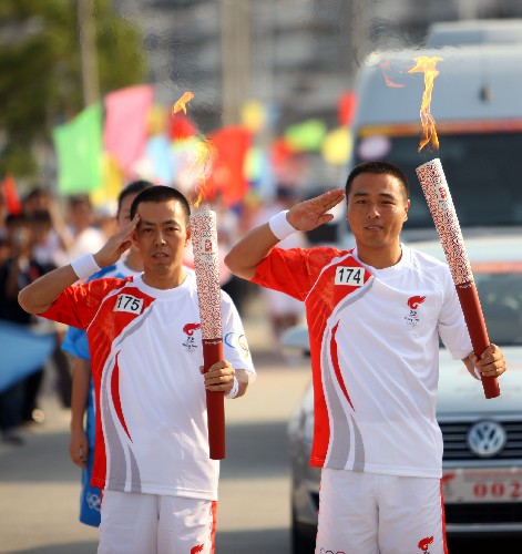 2008年奧運(yùn)會火炬在龍巖傳遞 5月13日,火炬手劉建飛(右)在長汀縣與下一棒火炬手張國興交接后向周圍群眾敬禮。當(dāng)日,北京奧運(yùn)圣火傳遞活動在福建省龍巖市舉行。 新華社記者邢廣利攝
