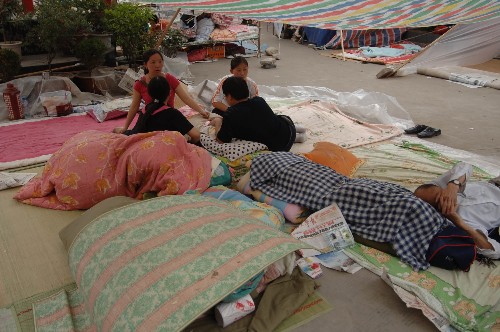5月15日,略陽(yáng)縣城居民在外露宿。 四川汶川地震發(fā)生后,毗鄰四川的陜西略陽(yáng)縣災(zāi)情嚴(yán)重??h城三分之二的建筑成危房,8萬(wàn)人住在街頭搭建的帳篷里。從地震當(dāng)天至15日晚,全縣20萬(wàn)城鄉(xiāng)人口約有八成有家難回。 新華社記者 丁海濤 攝