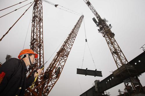 2月9日,一名施工人員在京滬高鐵上海虹橋站工地指揮鋼梁吊裝。