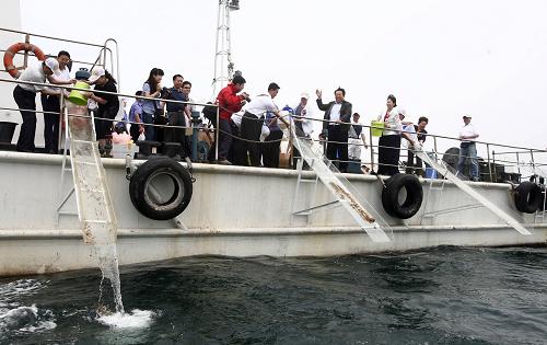 6月6日,青島市民在中苑碼頭參加增殖放流活動。 當(dāng)日,山東青島市舉行2009年漁業(yè)資源增殖放流啟動儀式,首批300萬尾對蝦、100萬只梭子蟹,3萬尾牙鲆和3萬尾梭魚投進青島太平灣海域。 新華社發(fā)(胡保勝攝)