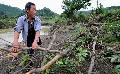 6月10日,在貴州省荔波縣茂蘭鎮(zhèn)羅家寨村的河道旁,村民劉文章正在清理河道。
