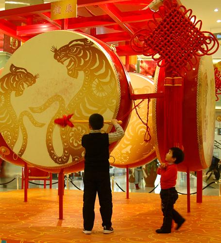 2月10日,在北京王府井東方新天地,兩名小朋友在大鼓前玩耍。新華社發(fā)(李文明 攝)