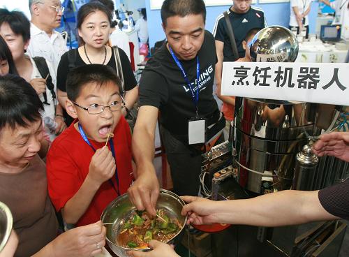 5月23日,在北京科博會(huì)上,觀眾紛紛品嘗烹飪機(jī)器人“炒”出的菜肴。新華社發(fā)(陳曉根 攝)