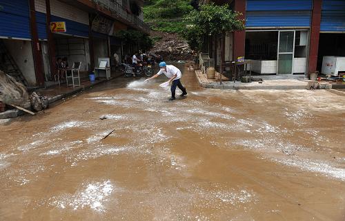 7月14日,達(dá)州市宣漢縣華景鎮(zhèn),衛(wèi)生防疫人員在對洪水沖過的路面消毒。新華社記者 江宏景 攝